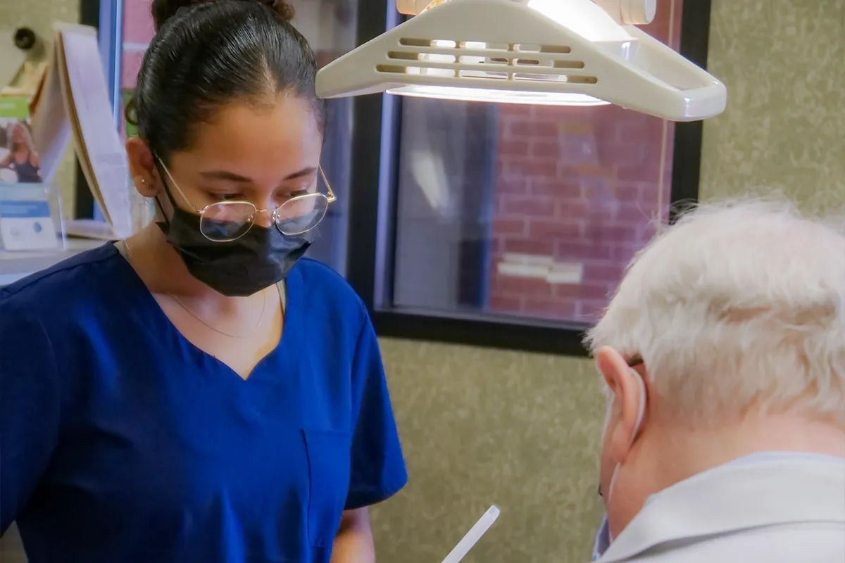 Dr. Hughes and dental assistant working on a dental bridge for a patient in the dentist's chair